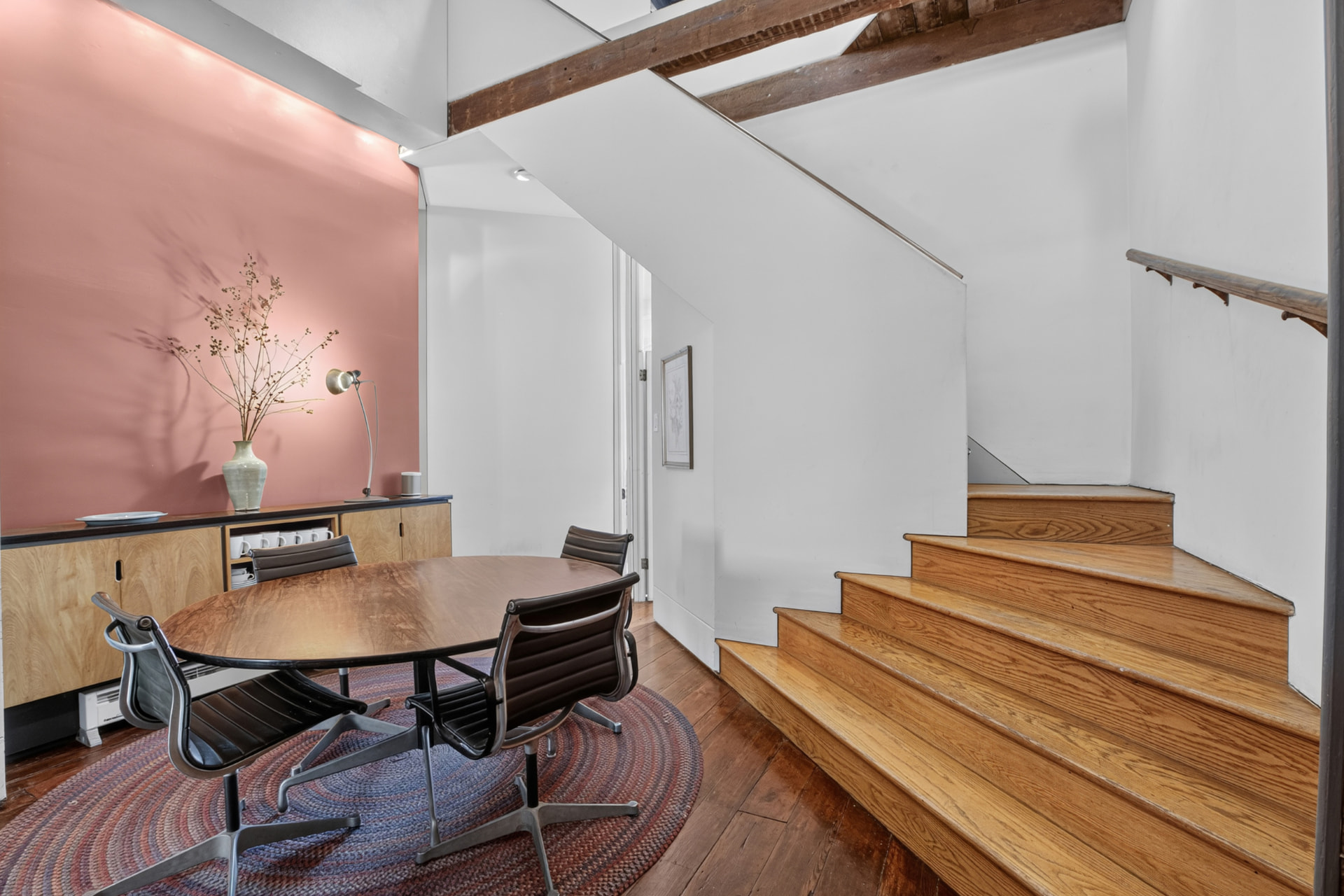 Dining area with round table, period stair and dusty rose walls
