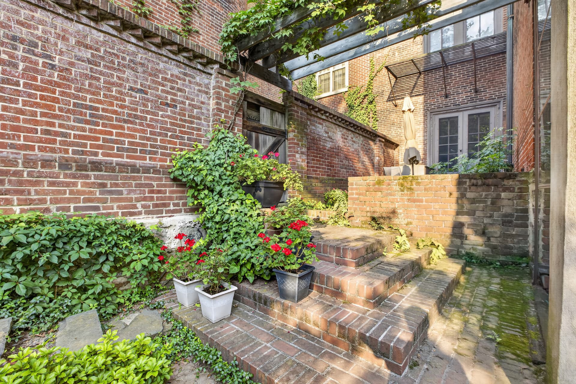 Brick garden steps with geraniums leading to the rear terrace